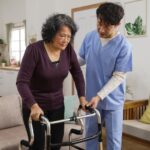 Physical therapist assists client standing and learning to use walker at home