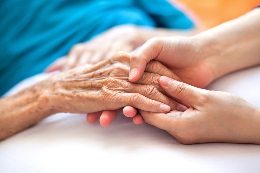 Close-up of a senior woman’s hand being held by a caregiver