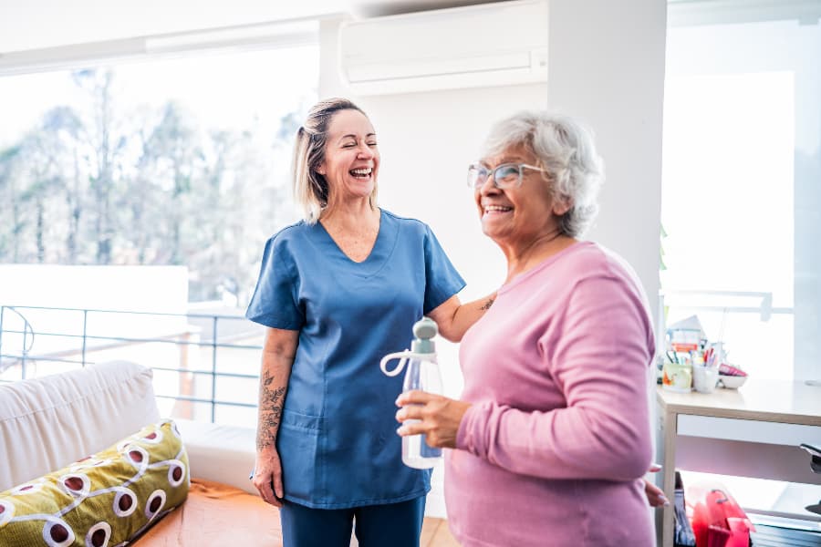 Happy senior and caregiver helping her at home